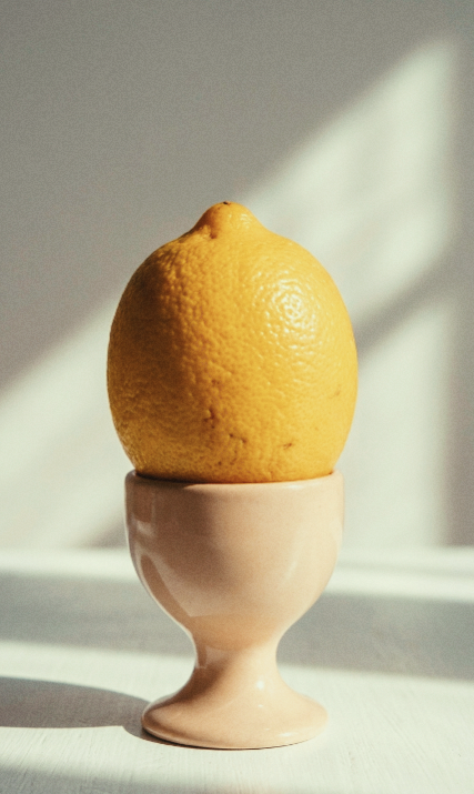 A lemon resting in a ceramic egg cup in soft sunlight